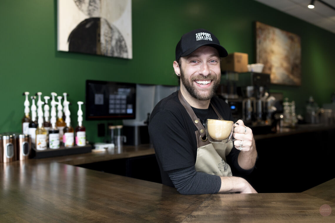 Photo: Barista, David Herman poses with a latte at the counter at Unity Java | Photo credit: Studio Luminoso by Christy McMahon